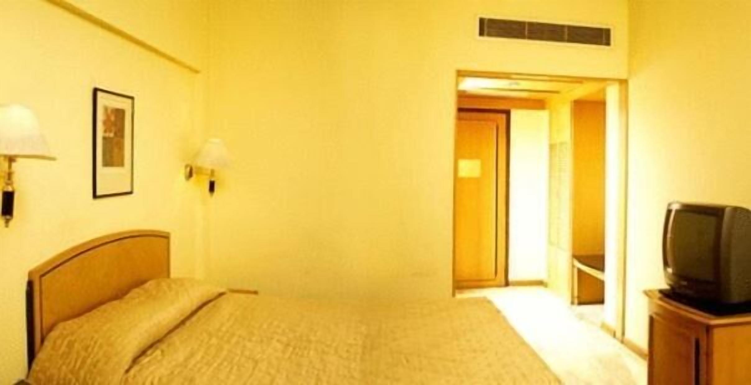 A hotel room with a bed, a television, and a door leading to another room.