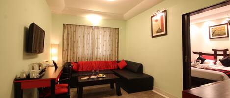 Una habitación de hotel compacta con sofá, una pequeña mesa de comedor y una cama.