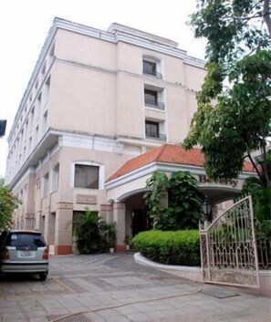 A multi-story building with a beige facade, a red-tiled roof, and a gated entrance. - Beverly Hotel (Chennai)