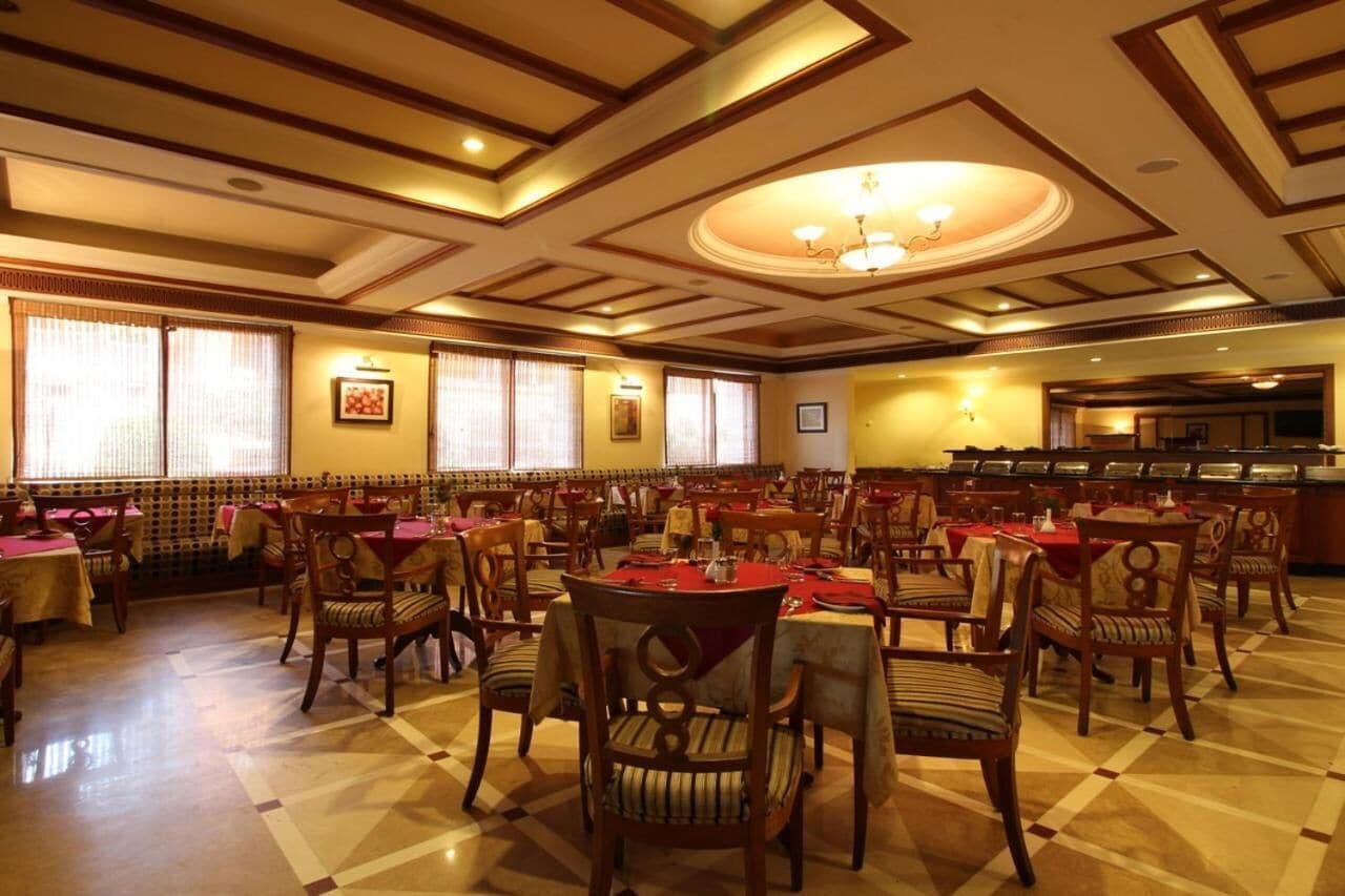 A spacious dining area with multiple tables and chairs, a buffet line, and a chandelier.