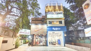 A multi-story building with a restaurant on the ground floor, a clothing store on the second floor, and a signboard advertising a pizza restaurant on the third floor. - MY BIZZ HOTEL (Pune)