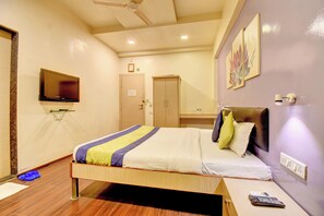 Habitación de hotel con cama, televisión, ventilador de techo, puerta y espejo.