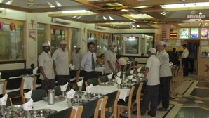 A dining area with long tables, chairs, and a wash basin. - Hotel Shreyas (Pune)