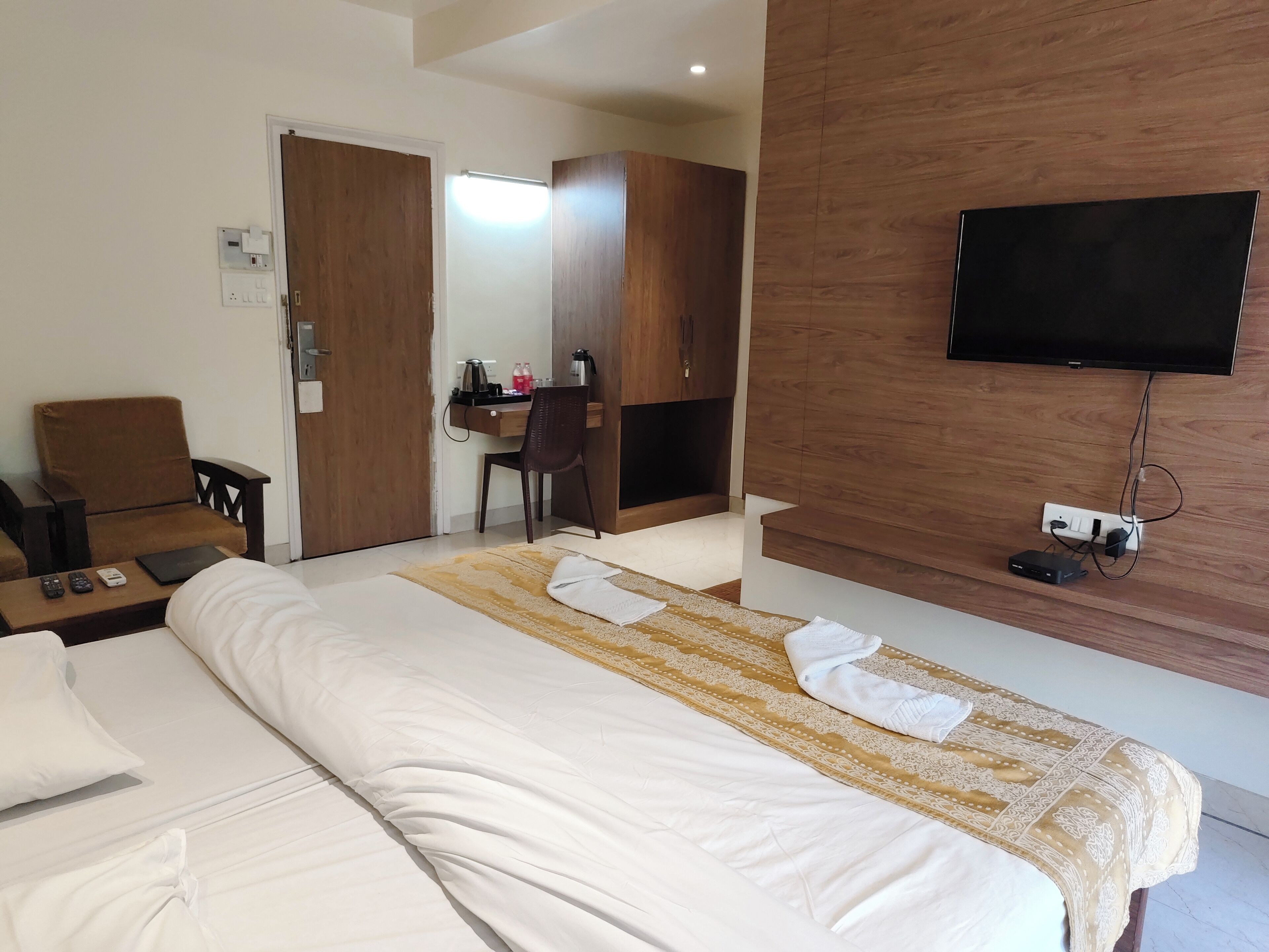 A hotel room with a bed, a desk with a chair, a television, and a wardrobe.