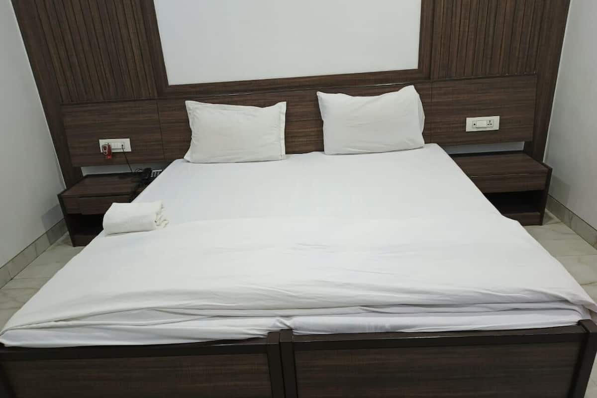 Una habitación de hotel estándar con una cama grande, dos mesitas de noche y un cabecero de madera.