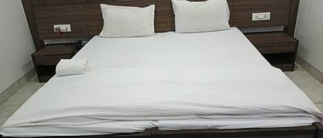 A standard hotel room with a large bed, two bedside tables, and a wooden headboard.