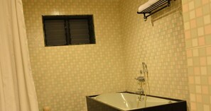 Un baño con bañera, ventana y perchero.