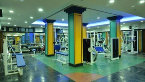 A gym with various exercise equipment, including weight machines and benches. - Hotel Kala Sagar (Pune)