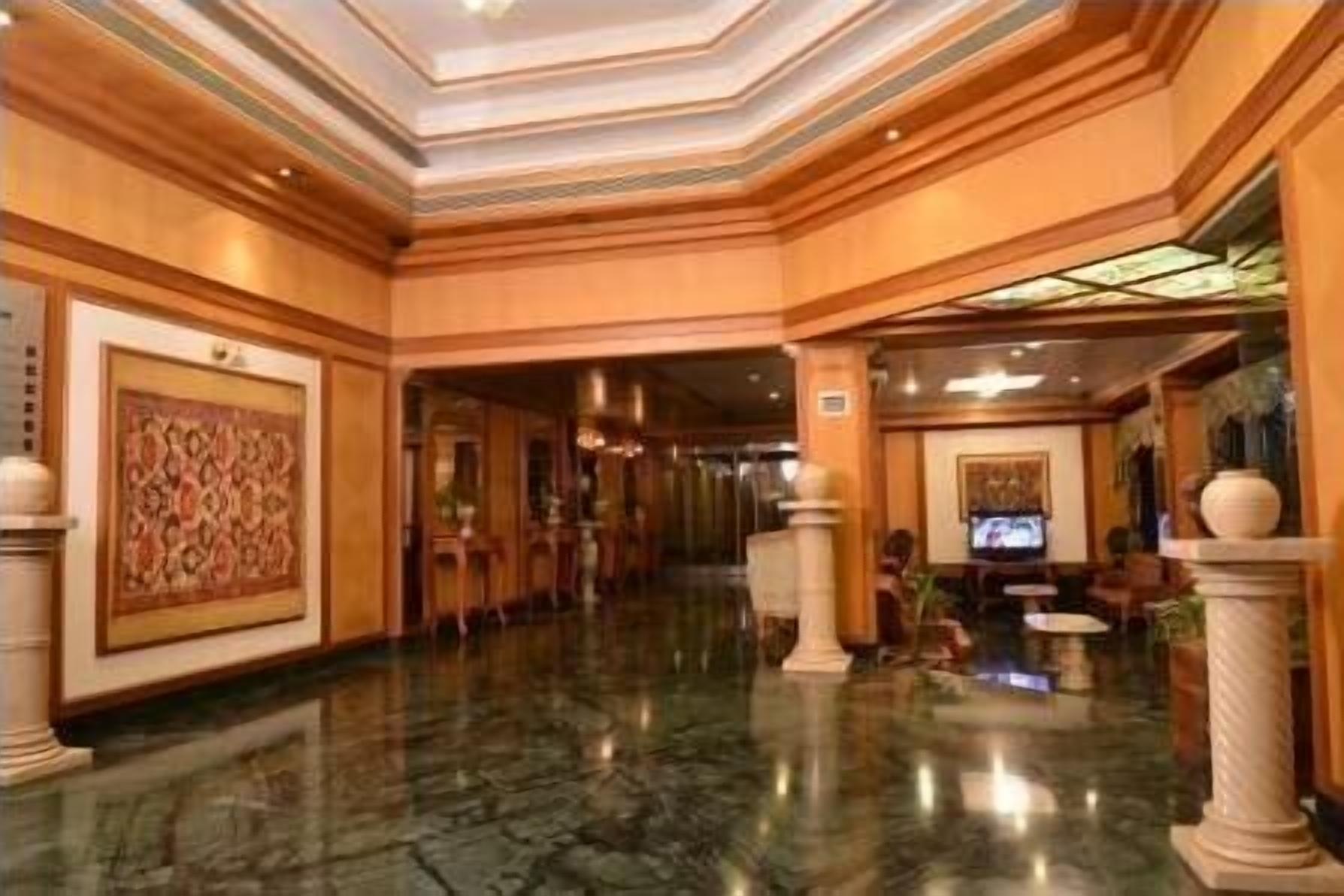 Un hall d’entrée spacieux, doté d’un sol en marbre, de boiseries et de grandes peintures décoratives.