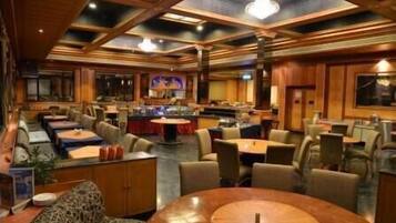 A spacious hotel lobby with multiple seating areas, a central bar, and a high ceiling with wooden beams.