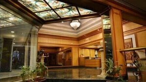 A hotel lobby with a high ceiling, a central chandelier, and a reception desk. - Hotel Kala Sagar (Pune)