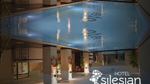 A hotel lobby with a central pool, multiple seating areas, and a visible reception desk. - Quality Silesian Hotel (Katowice)