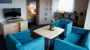 A room with a TV, a desk, a chair, a bed, and a window. - Quality Silesian Hotel (Katowice)