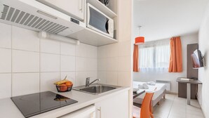 A compact kitchen with a microwave, sink, and a small countertop. - Appart'City Classic Marseille Aéroport – Vitrolles (Vitrolles)