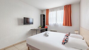 A hotel room with a bed, a desk, a TV, and a window with curtains. - Appart'City Classic Marseille Aéroport – Vitrolles (Vitrolles)