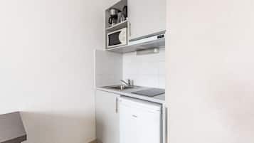 A compact kitchen with a built-in microwave, a sink, and a small refrigerator.