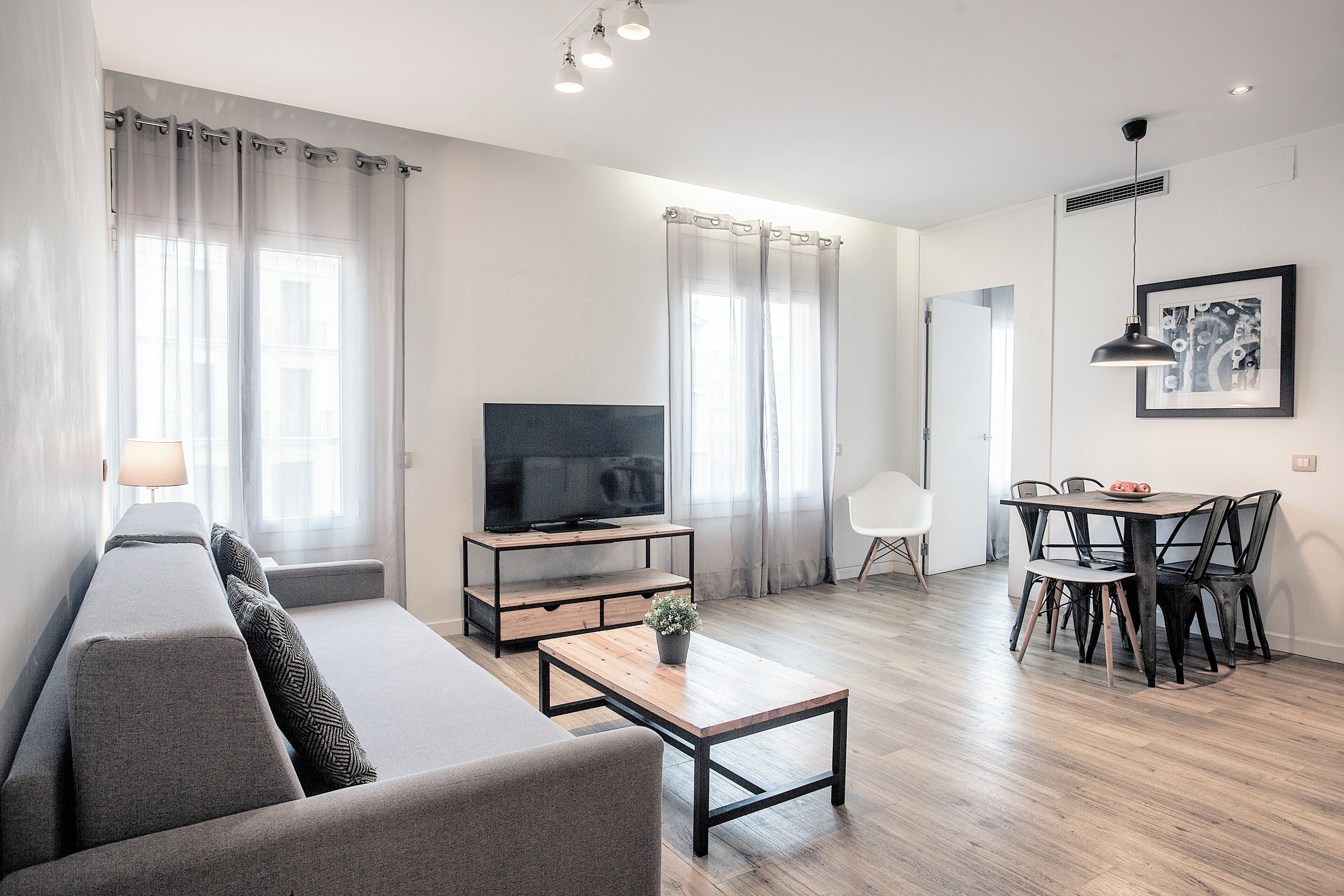 Una sala de estar moderna con sofá, televisor, mesa de centro y comedor.
