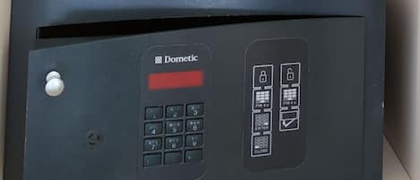 A room with a blue and white iron on a shelf and a black security device labeled "Dometic" below it.