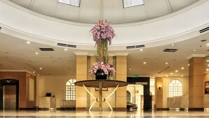 Un hall d’entrée spacieux, doté d’une table ronde centrale, d’un grand arrangement floral et d’un design de plafond moderne.