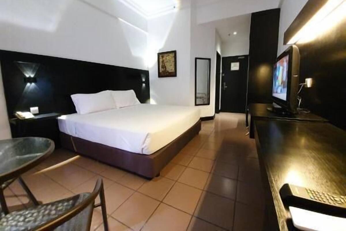 Une chambre d’hôtel équipée d’un lit, d’un bureau, d’une chaise, d’une télévision et d’un miroir.