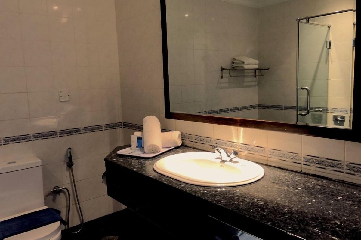 Une salle de bain avec un lavabo blanc, un miroir et un porte-serviettes.