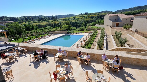 Un espacio para comer al aire libre con piscina y vistas a un paisaje montañoso.