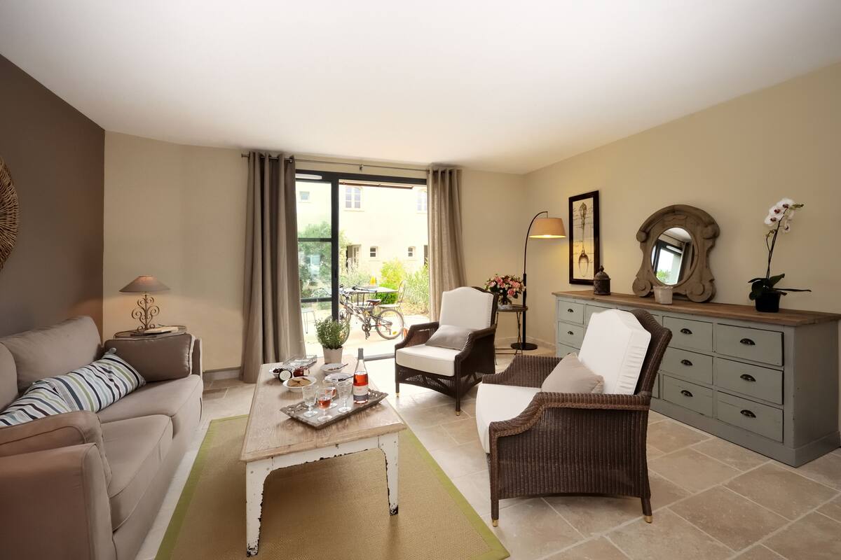 Een woonkamer met een bank, fauteuils, een salontafel, een eettafel, en een balkon met een fiets.