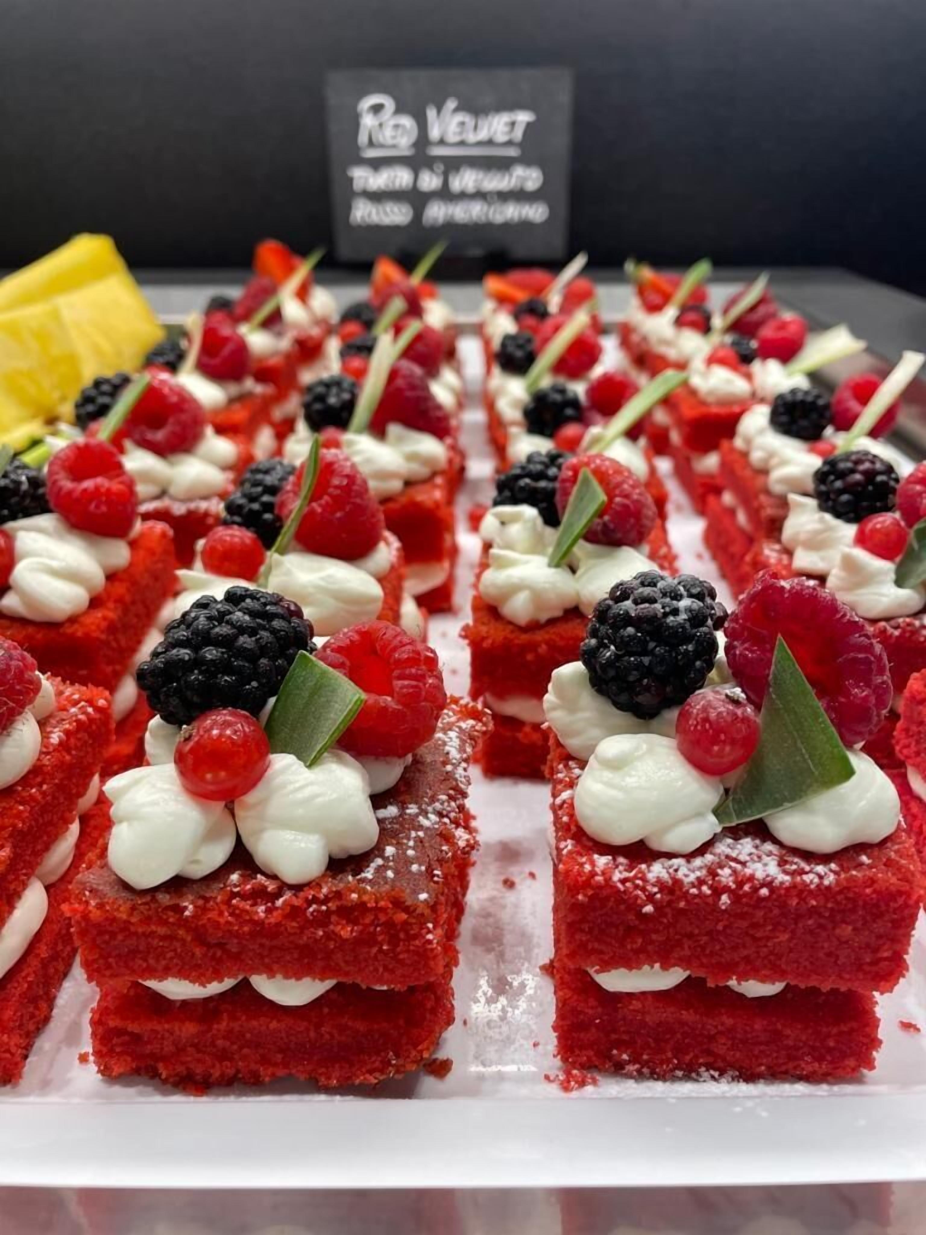 A display of red velvet desserts topped with cream and berries.
