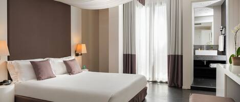 A hotel room with a large bed, bedside lamps, a desk with a mirror, and a view of the bathroom.