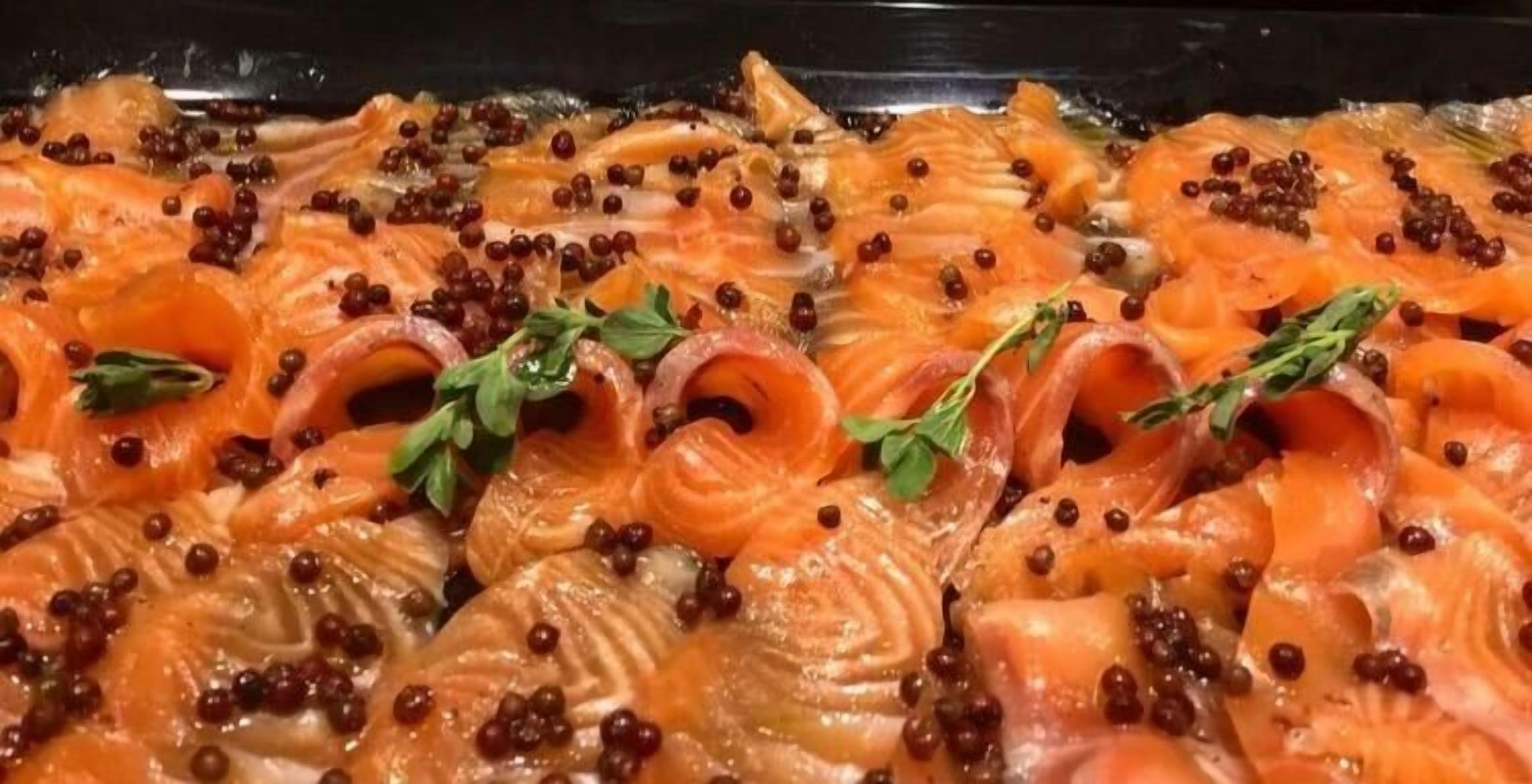 Close-up de fatias de salmão com caviar preto e ervas verdes.