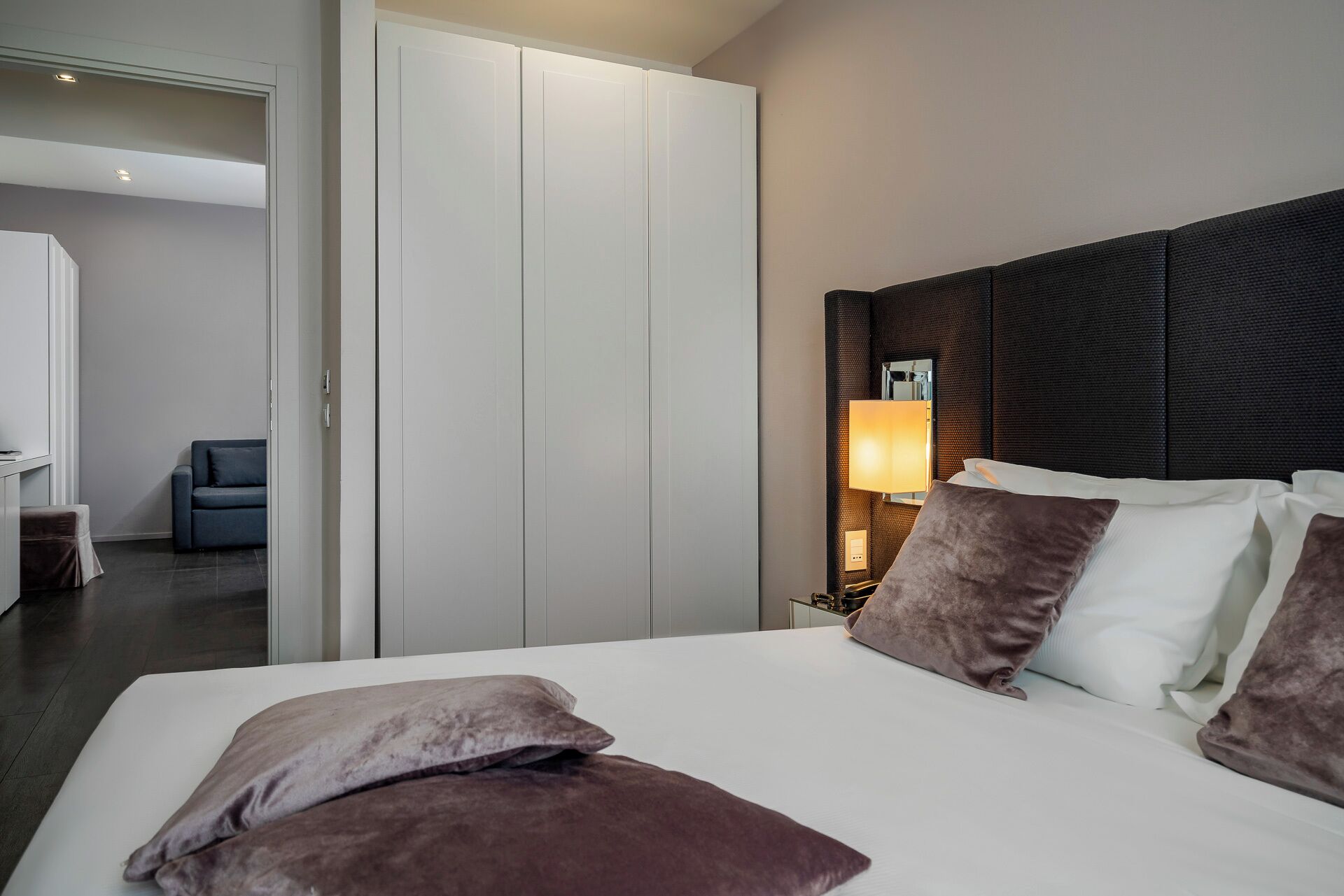 A hotel room with a large bed, a wardrobe, a desk, and a chair.