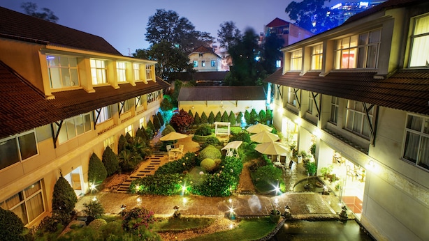 A courtyard with a central garden, steps leading to a building entrance, and a water feature. - Muong Thanh Da Lat (Xuan Huong - Da Lat)