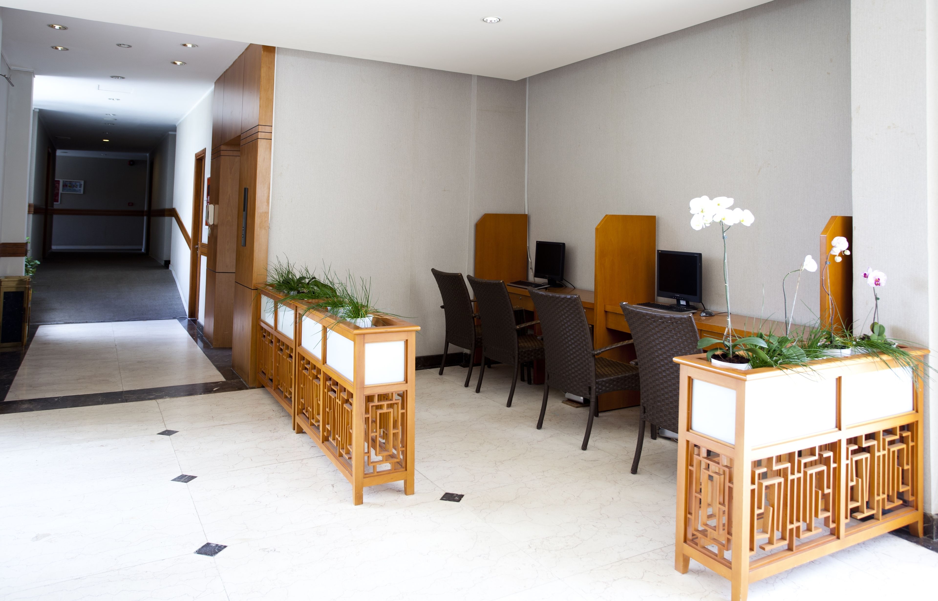 A hotel lobby with a reception desk, seating area, and a corridor leading to other rooms.