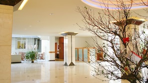 A spacious lobby with a polished floor, a reception desk, and a decorative tree. - Muong Thanh Da Lat (Xuan Huong - Da Lat)