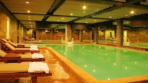A swimming pool with lounge chairs and a stone wall. - Muong Thanh Da Lat (Xuan Huong - Da Lat)