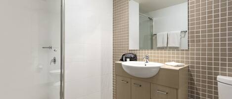 A bathroom with a glass-enclosed shower, a sink with a mirror above it, and a toilet.