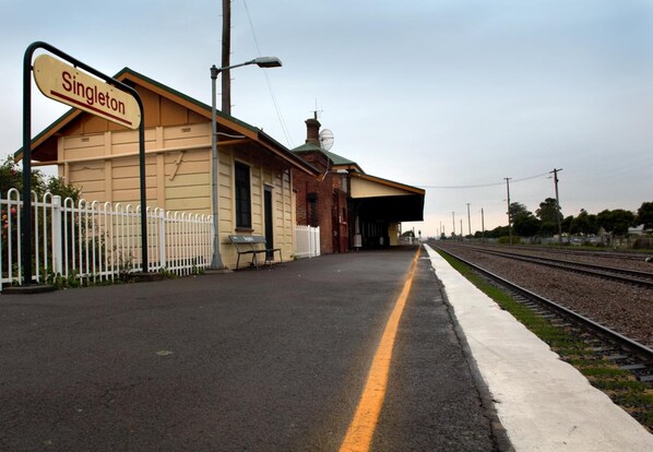 A train station platform with a sign reading "Singleton" and a fence.