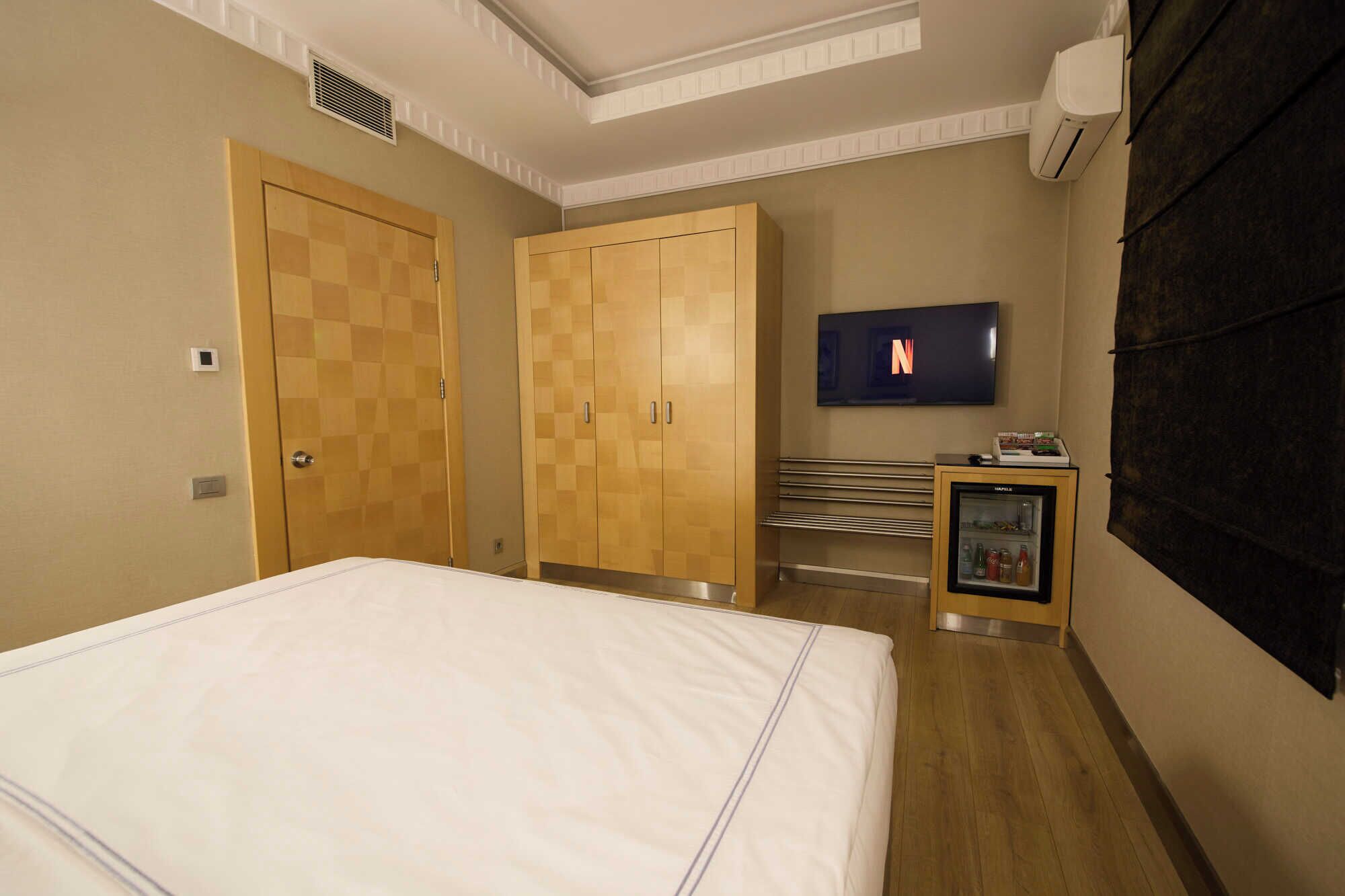 Ein Hotelzimmer mit Bett, Holzschrank, Fernseher und Minibar.