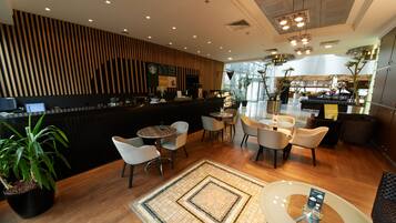 A modern interior with a reception desk, seating area, and a view of the kitchen.