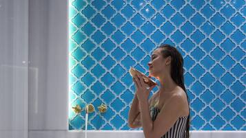 A woman sitting on a white bench in a bathroom with a blue patterned wall and a white sink.