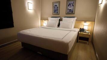 A hotel room with a large bed, two bedside tables with lamps, and two framed pictures on the wall.