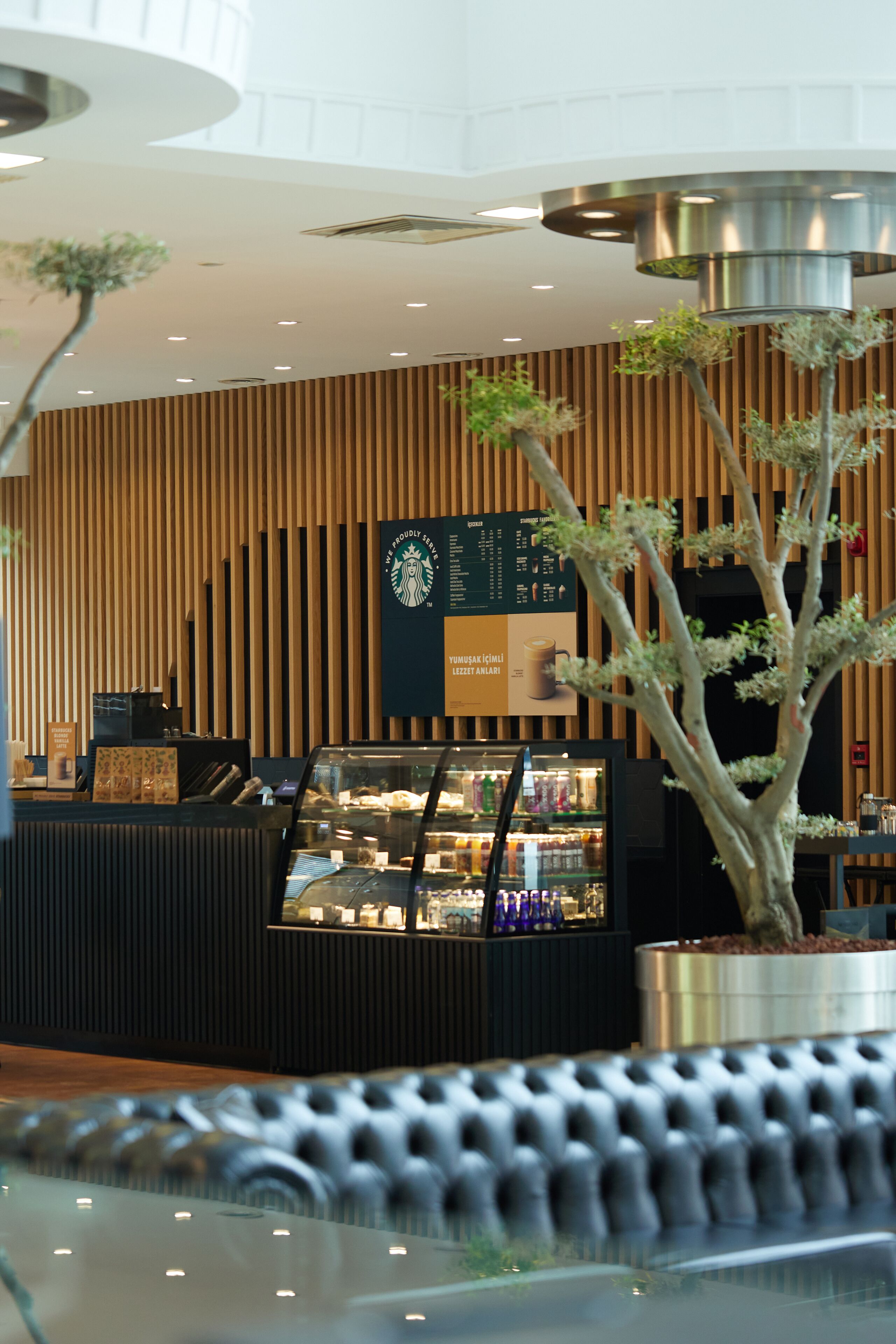 Un interior moderno con una mesa de recepción, una exhibición de café y un panel de pared de madera vertical.