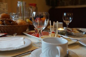 A dining table with plates, glasses, and a basket of bread.