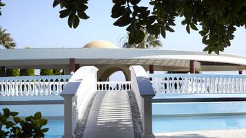 Zona de piscina con balaustrada blanca y una estructura abovedada al fondo.