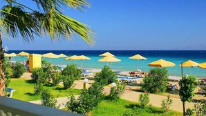 A beachside view with multiple yellow umbrellas, lounge chairs, and a clear view of the ocean.