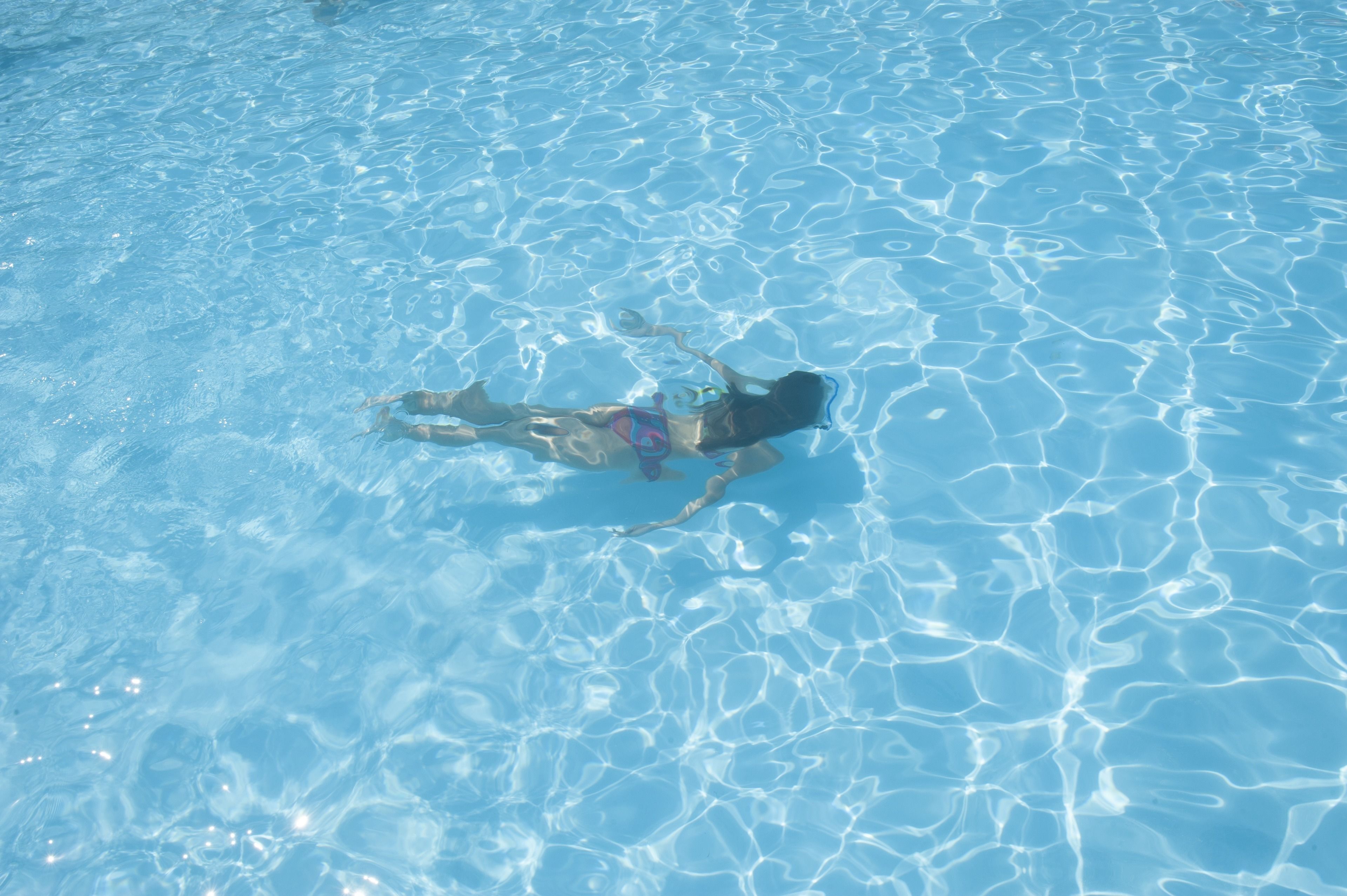 A person swimming in a clear blue pool.