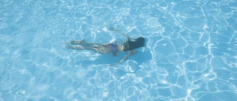 A person swimming in a clear blue pool.