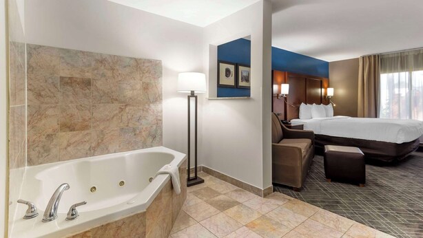 A hotel room with a large bathtub, a bed, a sofa, and a desk. - Comfort Suites Atlanta Airport (Atlanta)