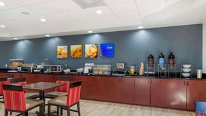 A modern breakfast area with a counter, seating, and various food items. - Comfort Suites Atlanta Airport (Atlanta)