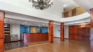 A spacious lobby with a reception desk, wooden pillars, and a chandelier. - Comfort Suites Atlanta Airport (Atlanta)